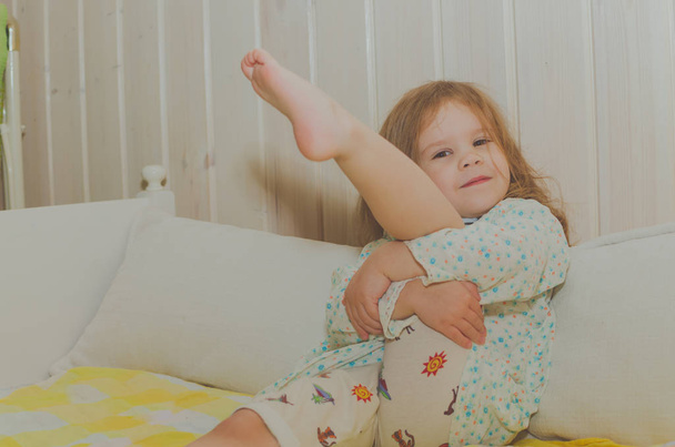 dziewczynka w łóżku siedzi przytulanie nogi - Zdjęcie, obraz