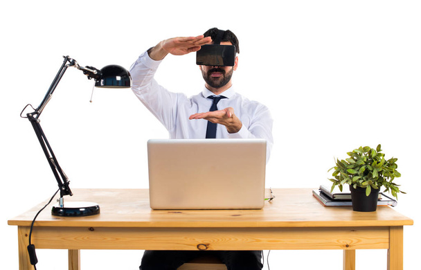 Empresario en su oficina usando gafas VR sosteniendo algo
 - Foto, imagen
