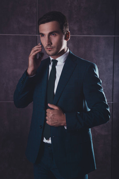 Portrait of serious young businessman talking on phone with clie - 写真・画像