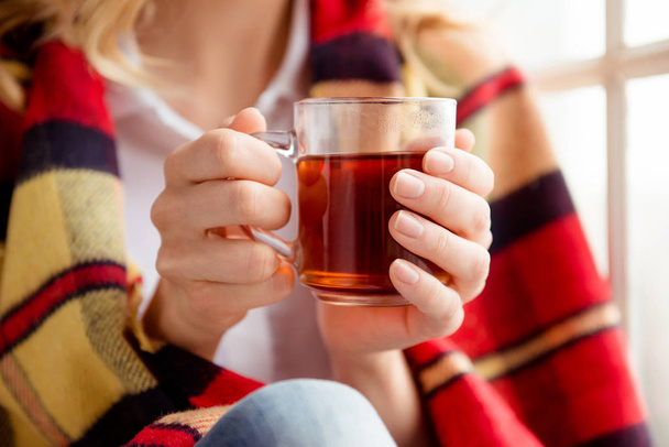 Close up of women covering with plaid and holding cup of tea - Foto, imagen