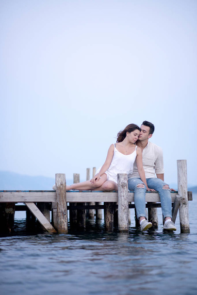 Happy couple sitting on a pier on summer vacation - Φωτογραφία, εικόνα