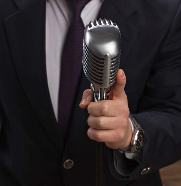 Man holding a retro microphone over black background - Фото, зображення