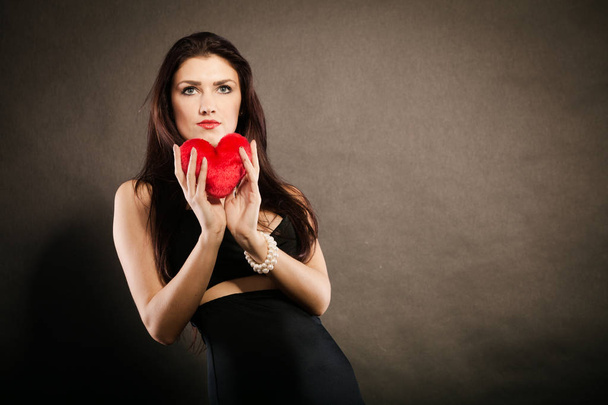 Beautiful woman holds red heart on black - Fotoğraf, Görsel
