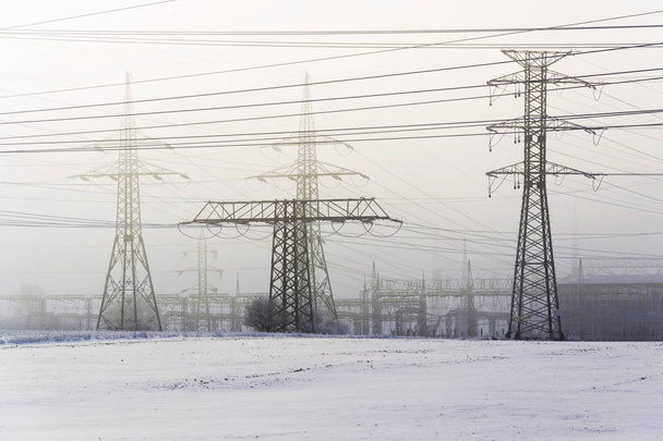 Pylônes d'électricité de la centrale de distribution dans le gel hivernal brumeux
 - Photo, image