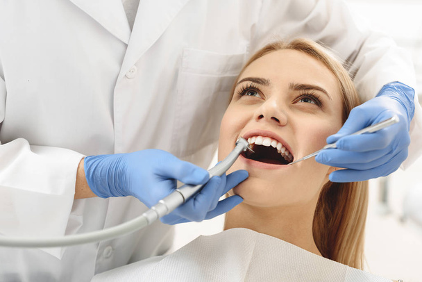 Dentist starting common operation of cleaning female mouth - Foto, Imagen