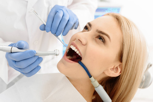 Stomatologist treating tooth of woman - Fotoğraf, Görsel
