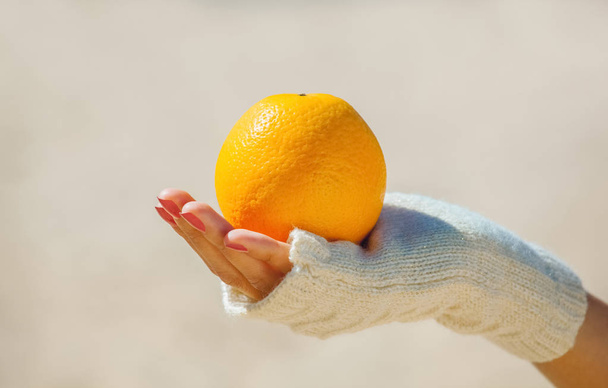Дівчина в білих рукавичках тримає стиглий апельсин. Падіння надмірної ваги
. - Фото, зображення