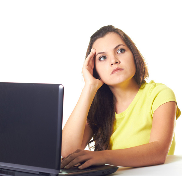Attractive young woman in a yellow shirt working on laptop and l - 写真・画像