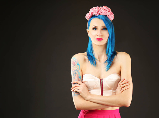Beautiful young woman with stylish color hair and tattoo on dark background - Foto, Imagem