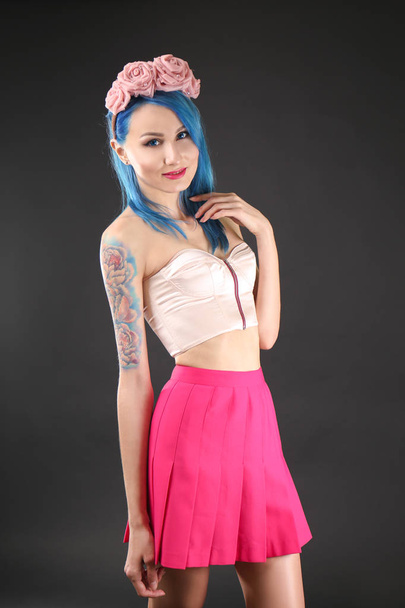 Beautiful young woman with stylish color hair and tattoo on dark background - Foto, Imagen
