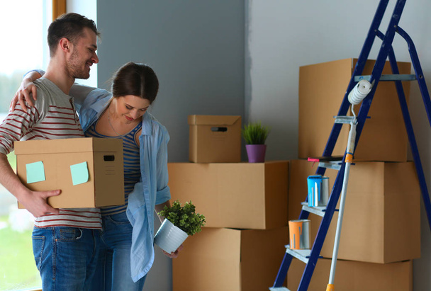 Felice giovane coppia disimballaggio o scatole di imballaggio e trasferirsi in una nuova casa
 - Foto, immagini