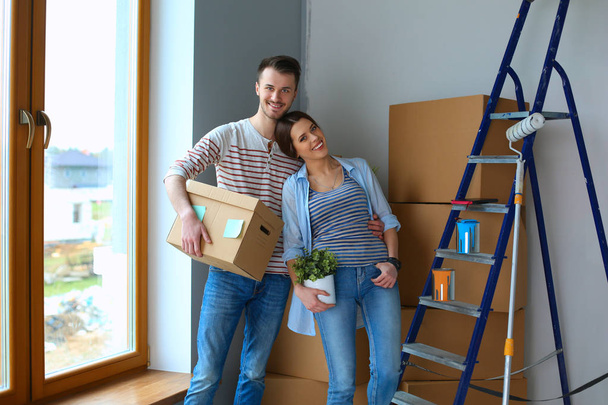 Happy young couple unpacking or packing boxes and moving into a new home - Foto, afbeelding