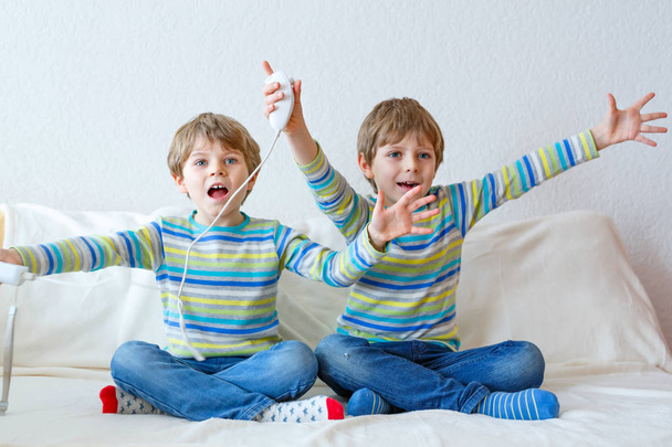Dois garotinhos jogando videogame em casa
 - Foto, Imagem
