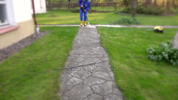 Gosposia człowiek mycia betonu ścieżki w pobliżu jego domu. - Materiał filmowy, wideo