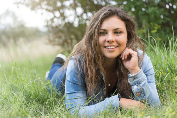 Smiling attractive teenage girl with long hair outdoors - Фото, изображение