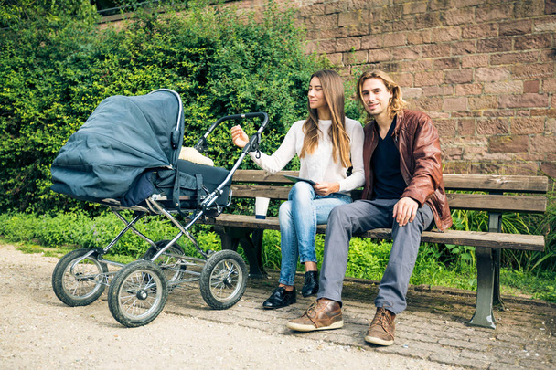 Young Parents With Baby Stroller In The Park - Foto, Imagem