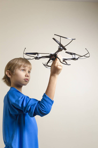 Little kid playing with drone. Boy holding quadcopter in his hand, preparing to fly - 写真・画像