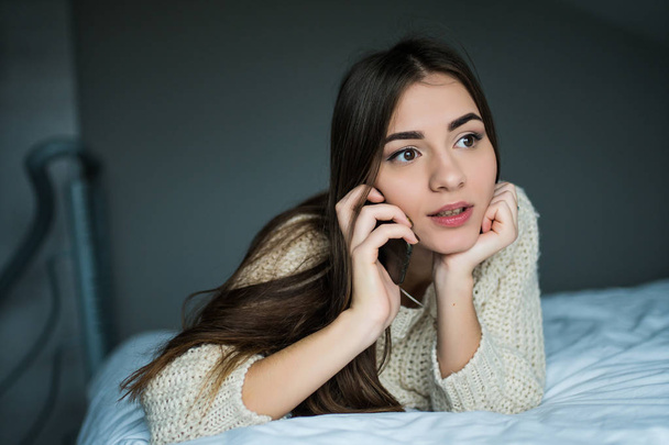 Дівчина розмовляє телефоном у ліжку
  - Фото, зображення