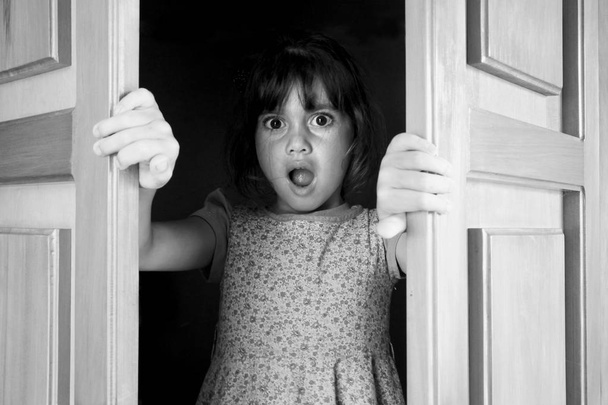 Молода дівчина здивована, щоб знайти і подивитися, що стоїть за закритими дверима
 - Фото, зображення
