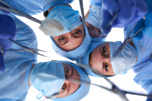 Surgeons team, woman wearing protective uniforms,caps and masks - Fotó, kép