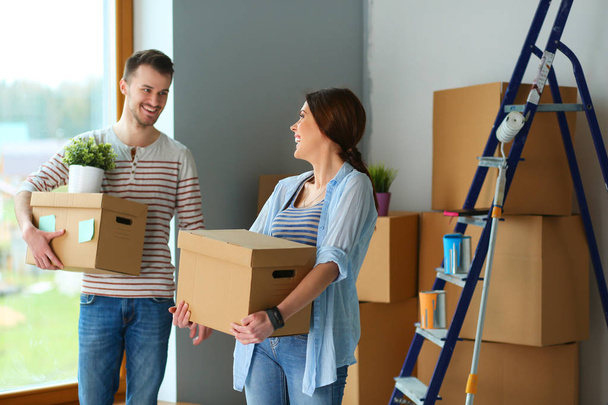 Happy young couple unpacking or packing boxes and moving into a new home - Foto, imagen