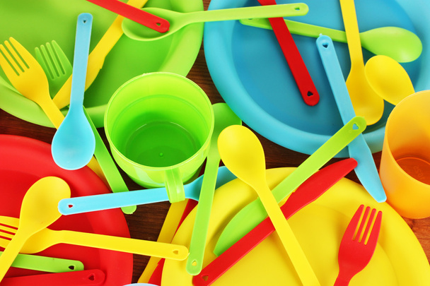 bright plastic disposable tableware on wooden background close-up - Zdjęcie, obraz