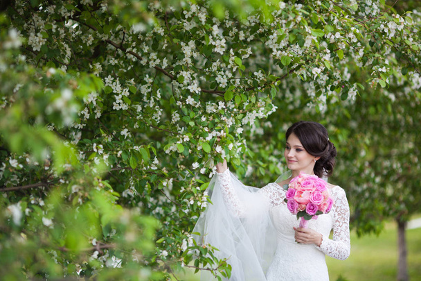 Young beautiful woman, bride with wedding bouquet in blooming garden - Фото, зображення