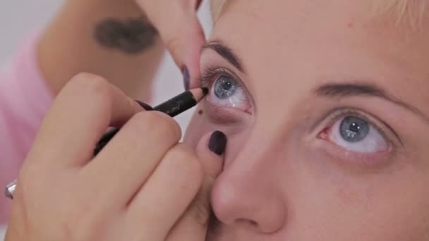 Maquillaje profesional artista aplicando delineador de ojos alrededor de todo el ojo del modelo
 - Metraje, vídeo