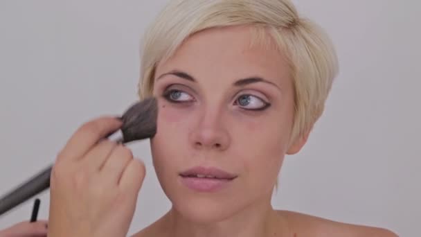 Artista de maquillaje profesional aplicando polvo a la cara de la mujer
 - Metraje, vídeo
