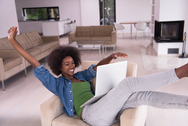 African American woman at home in the chair using a laptop - Foto, imagen