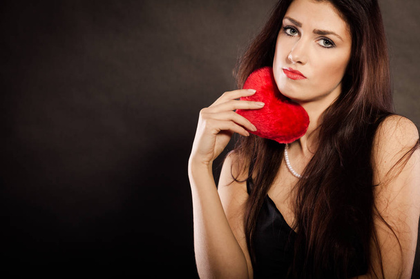 Sad lovely woman holds red heart on black - Foto, immagini