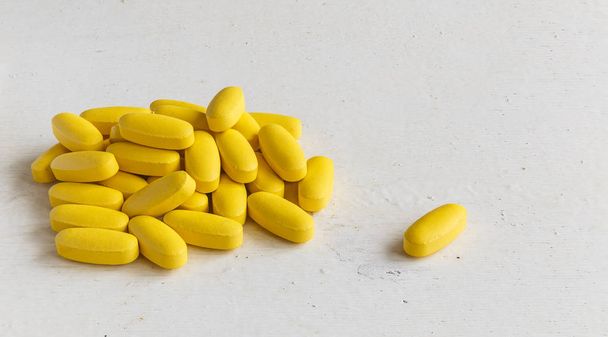 Vitamine pillen liggend op een houten plank geschilderd - Foto, afbeelding