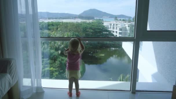Mała dziewczynka stojący w pobliżu duże szerokie okna i z zadowoleniem przyjmuje samolot który zamierzać lądowania - Materiał filmowy, wideo