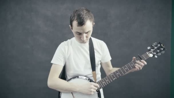 Young man plays the banjo. Black background - Imágenes, Vídeo