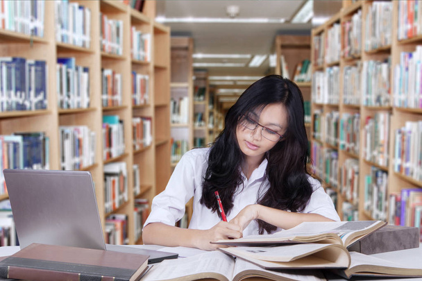 Attractive student with long hair studying in library - 写真・画像
