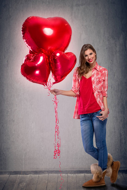 Young girl holding bright red balloons - Foto, afbeelding