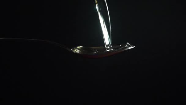 Hidasliikkeinen lähikuva video öljystä kaadetaan lusikalla mustalla taustalla
 - Materiaali, video