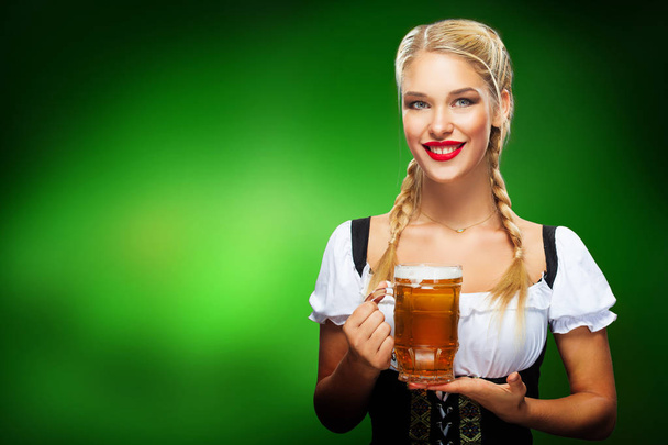 St Patricks Day. Young sexy Oktoberfest waitress, wearing a traditional Bavarian dress, serving big beer mugs on blue background with copy space - Valokuva, kuva
