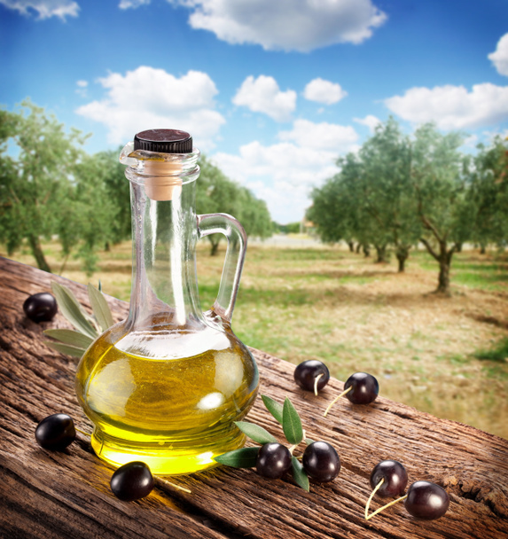 Black olives with bottle of oil on a wooden table. - Foto, Imagen