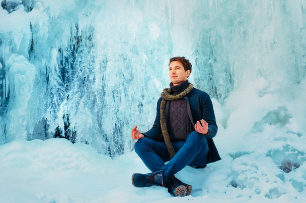jovem sentado no snowdrift neve na floresta e olhando para o rio de inverno
 - Foto, Imagem