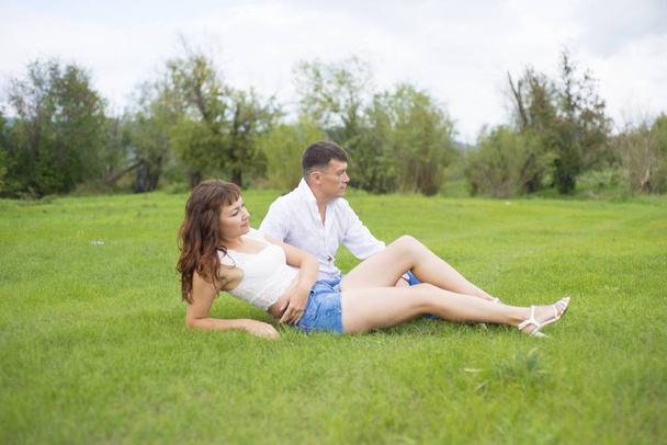 Lovers man and woman sitting on the green grass. - Foto, Imagen