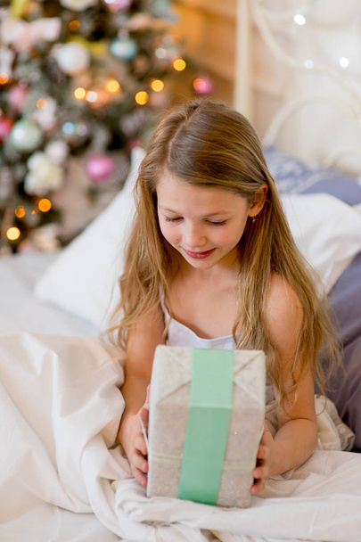 Child girl wake up in her bed in Christmas morning - Foto, afbeelding