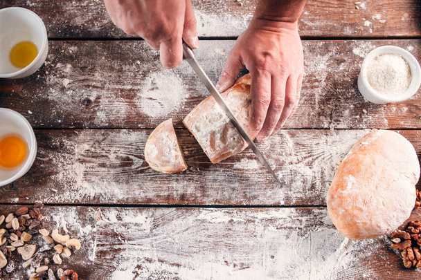Cutting homemade bread on kitchen table flat lay - Photo, image