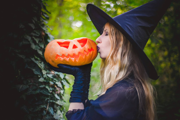 Feliz Halloween bruxa menina mantém abóbora laranja
 - Foto, Imagem