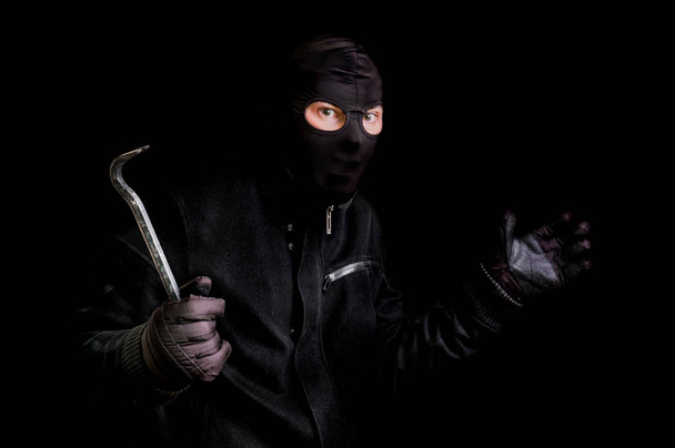 Ladrón enmascarado en pasamontañas con palanca aislada en negro
 - Foto, imagen