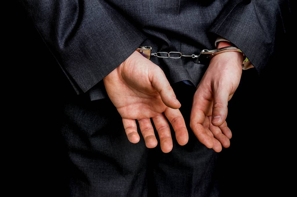 Empresário preso algemado com as mãos atrás das costas
 - Foto, Imagem