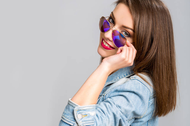 Fashion model with straight hair wearing sunglasses and denim jacket - Foto, imagen