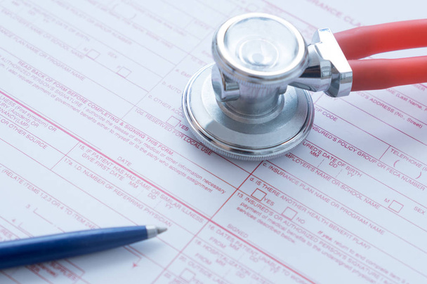 Formulario de reclamo de seguro de salud con pluma y estetoscopio
 - Foto, imagen