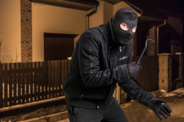 Μασκοφόροι κλέφτης σε balaclava με λοστό θέλει να ληστέψει ένα σπίτι - Φωτογραφία, εικόνα