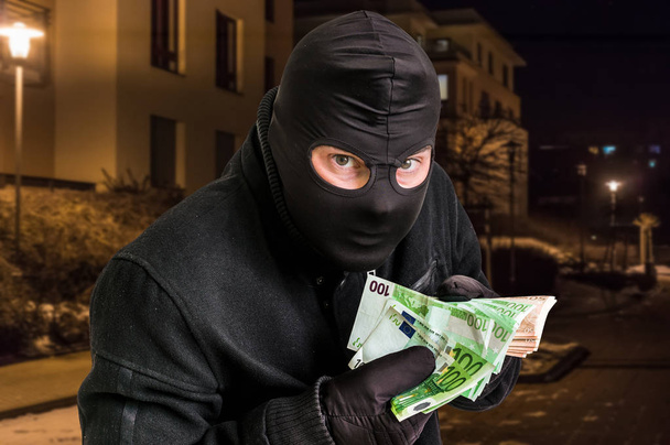 Masked thief in balaclava with stolen money - Φωτογραφία, εικόνα
